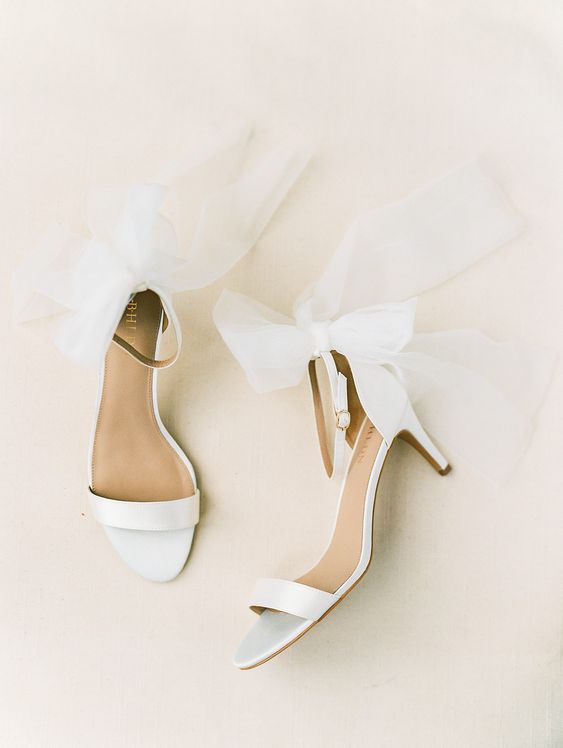 minimalist white wedding shoes with ankle straps and large bows attached plus kitten heels for more comfort