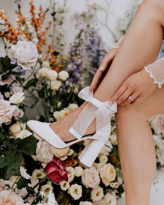 white pearl wedding shoes with block heels and bows on the ankles are a very cute and lvoely solution for a wedding