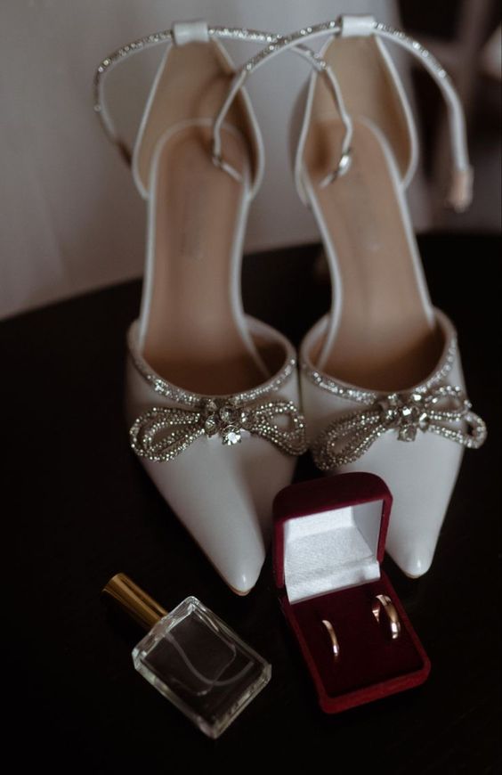 white pointed toe wedding shoes with embellished ankle straps and bows are gorgeous for a chic and glam bride