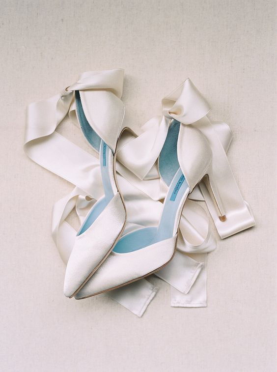 white satin wedding shoes with not very high heels and ribbons to make bows are classic for any bridal look