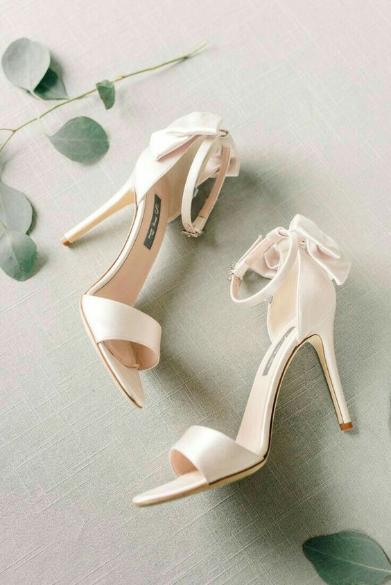 white wedding shoes with ankle straps and bows on the back are a cool idea for a spring or summer wedding, they are classic