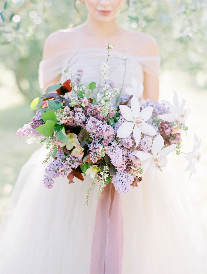 The wedding bouquet contained much lilac and leaves, and a mauve ribbon highlighted it