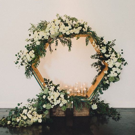 oversized hexagon wedding backdrop with lush greenery, candles and white blooms