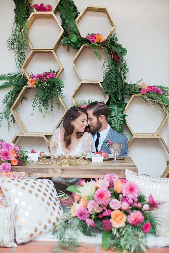 hexagon sweetheart table backdrop with lush greenery and bold blooms