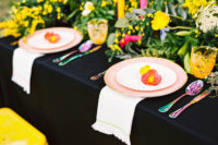 09 The table setting was done with a black tablecloth, pink plates, colorful flatware and neon-colored candles