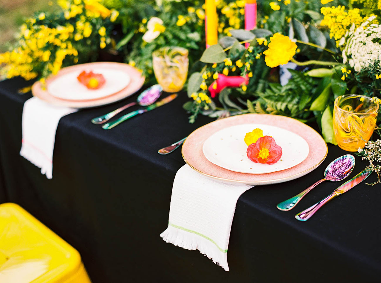 The table setting was done with a black tablecloth, pink plates, colorful flatware and neon colored candles