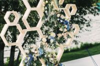 09 a honeycomb wedding backdrop decorated with lush greenery, neutral and blue flowers