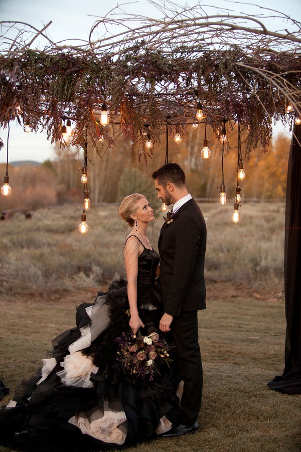 a black wedding dress wiith spaghetti straps and a layered tulle skirt with cream touches, a black veil