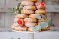 13 a stack of glazed donuts topped with foliage and fresh roses
