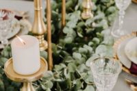 17 elegant gold candle holders with white candles and a lush eucalyptus garland