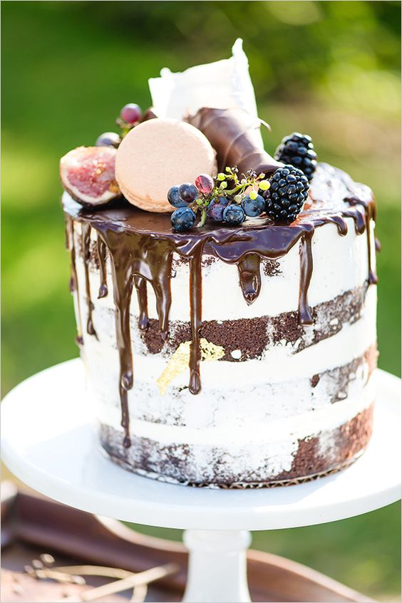 chocolate cake with chocolate drip, topped with grapes, blackberries, figs, macarons