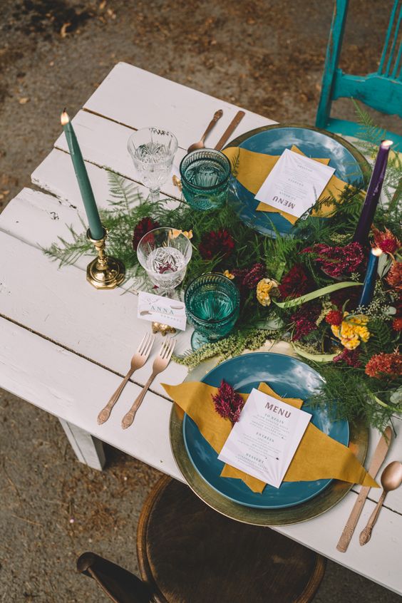 a jewel tone weding table setting with teal and mustard touches