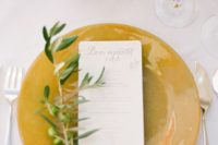 21 a mustard charger with an olive branch and baby’s breath for a fall tablescape