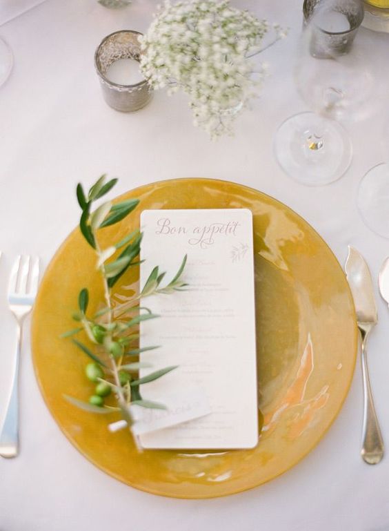 a mustard charger with an olive branch and baby's breath for a fall tablescape