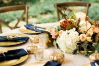 23 a fall tablescape with gold chargers, navy napkins and gilded pumpkins