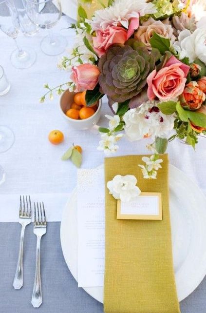 a neutral tablescape with a bold floral centerpiece and a mustard napkin