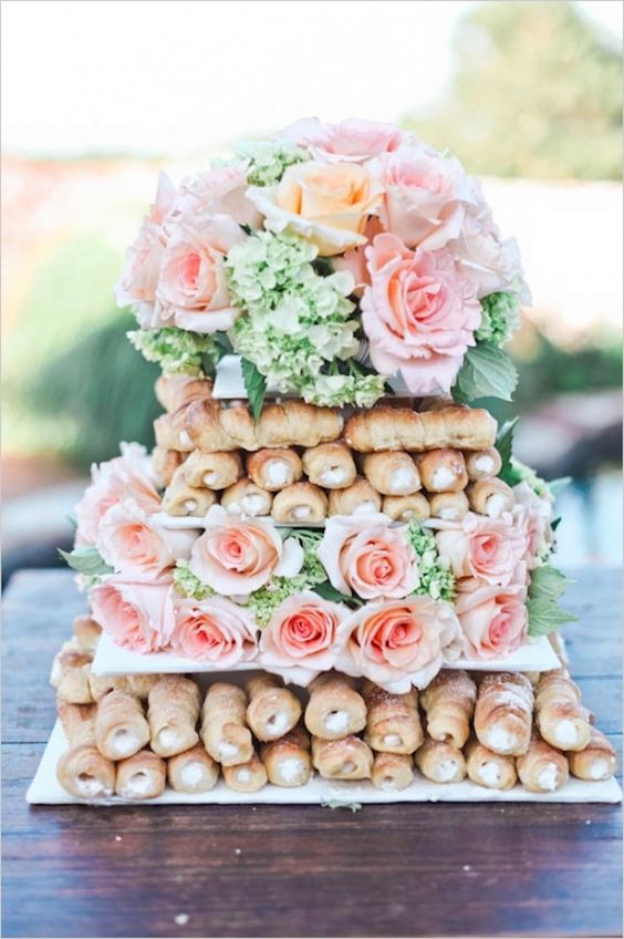 cannoli tower cake displayed with fresh pink roses