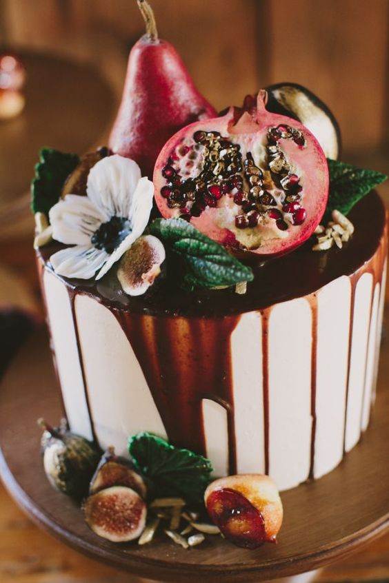 iced wedding cake with a pomegranate drip, with pomegranates, figs and pears