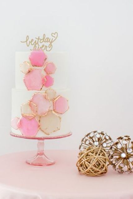 a wedding cake decorated with pink honeycombs with a gilded edge