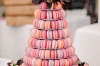 29 a macaron wedding tower in pink and peachy shades topped with florals and foliage