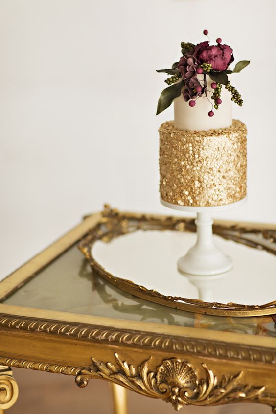 gold and white wedding cake with moody florals on top