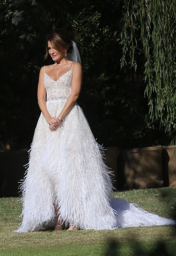 a beautiful glam A-line wedding dress with a V-neckline, a feather skirt with a train and embellishments is a fantastic idea
