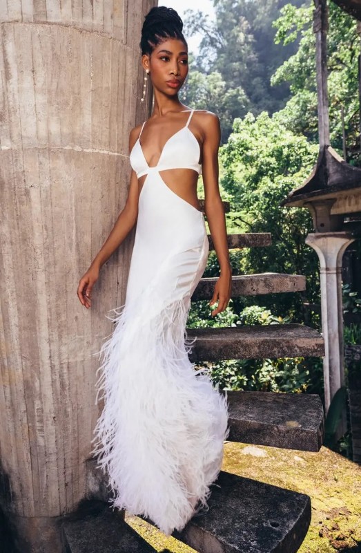 a chic modern plain wedding dress with spaghetti straps, side cutouts, a feathered skirt and pearl earrings for a sexy bridal look