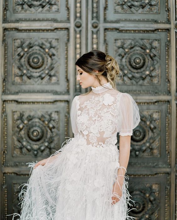 a glam and sophisticated wedding dress with a lace applique bodice and puff sleeves plus a feather skirt is very beautiful