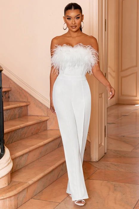 a modern plain strapless wedding jumpsuit with a feathred neckline plus white shoes compose a great look for a modern bride