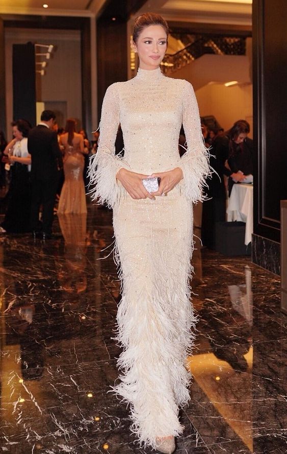 a shiny nude wedding dress with a turtleneck, feathered sleeves and a skirt is a great and chic idea for a glam bride