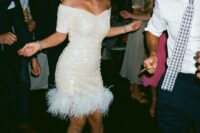 a white sequin off the shoulder over the knee dress with feathers is ideal for a wedding reception for a fun glam wedding