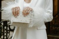 a wihte feather mini dress plus a white feathered blazer, statement earrings and an embellished clutch for a modern glam bridal look
