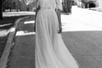 an elegant off the shoulder A-line wedding dress with beading and feathers on the bodice, skirt and straps