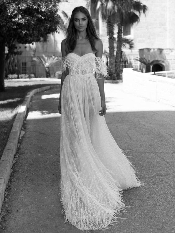 an elegant off the shoulder A-line wedding dress with beading and feathers on the bodice, skirt and straps