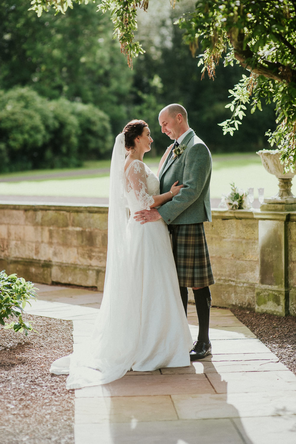 The bride was wearing an illusion neckline wedding dress with half sleeves and a veil, the groom was wearing a jacket and a traditional kilt, all in matching colors