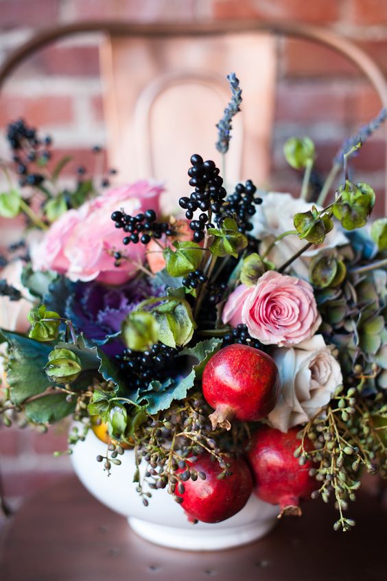 a beatiful centerpiece with pomegranates, berries, pink and white roses for a fall or late summer wedding