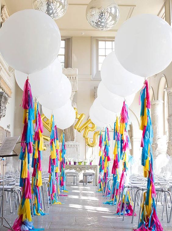 oversized white balloons with colorful fringe for decorating a wedding aisle