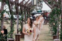 03 unique wedding aisle with wood arches interwoven with greenery and decorated with candle lanterns