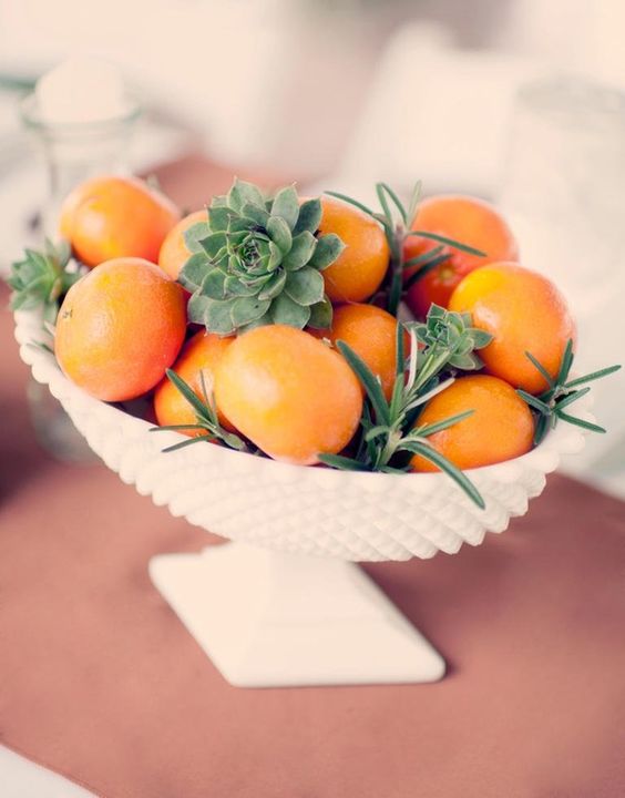 a white bowl with tangerins, succulents and herbs for a summer or tropical wedding