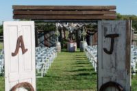 04 rustic wedding ceremony space with wooden arches and signs and vintage doors