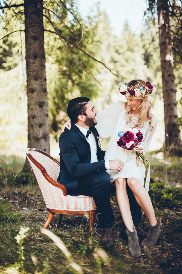 the bride was wearing a mini boho wedding dress with long sleeves and lace detailing and a bold floral crown, brown ankle booties finished her look