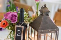 05 a metal candle lantern, a fuchsia floral arrangement and a chalkboard bottle table number for a vineyard celebration