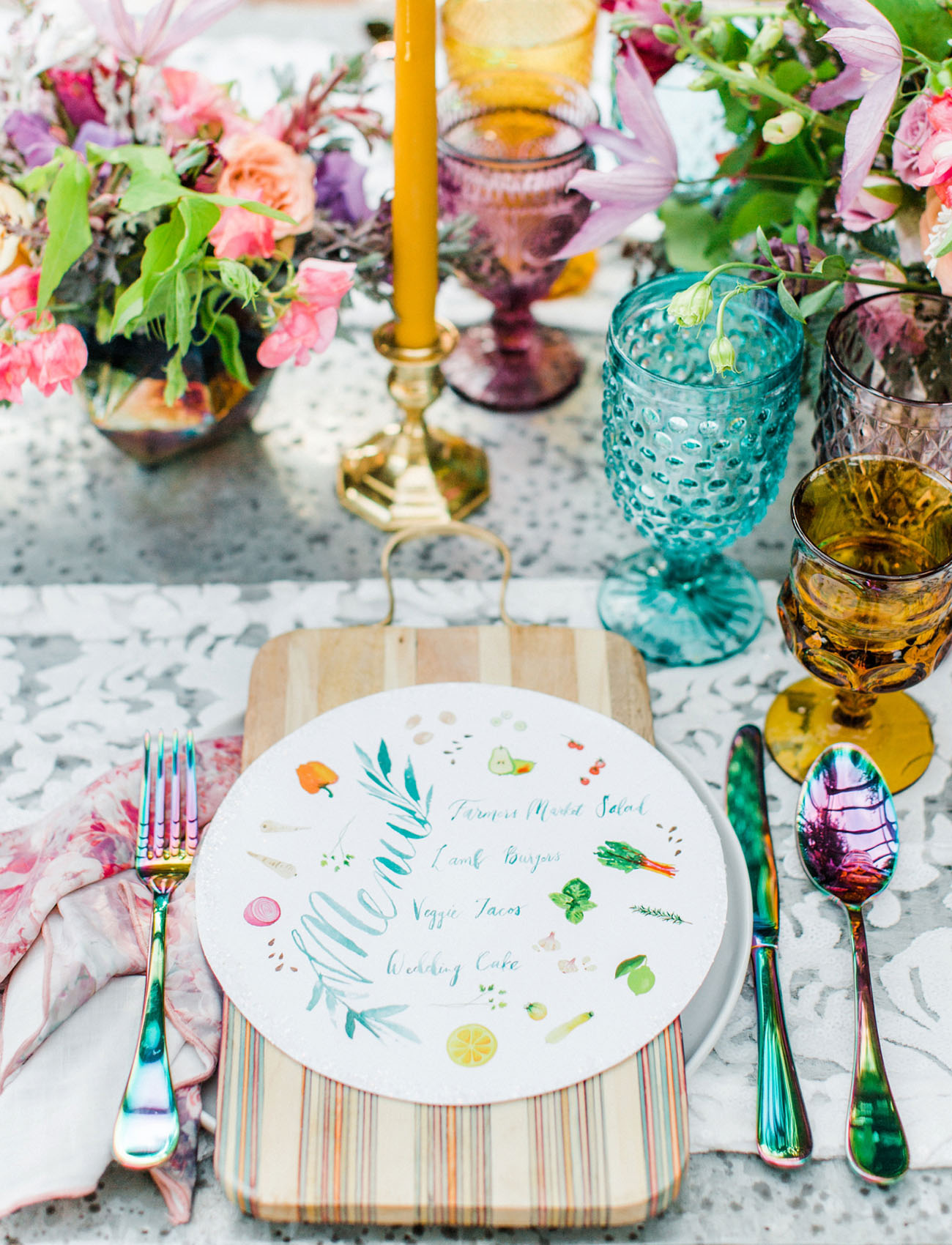 The wedding table setting was done with colorful glasses, bold blooms, printed menus and colorful cutlery