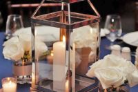 06 a modern shiny metal candle lantern, some small candles and white rose arrangements for an elegant wedding