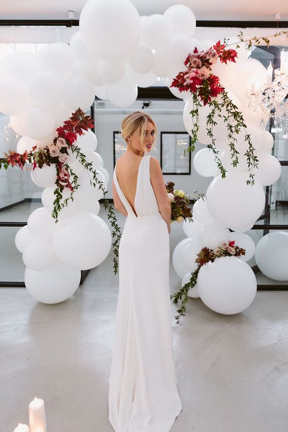 a wedding arch of oversized white balloons, foliage and dusty pink roses