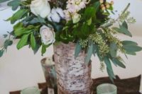 11 a wedding centerpiece with a cow skin, copper and mint candle holders, a bark centerpiece with greenery, white roses and cotton