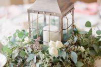 11 a whitewashed candle lantern on a eucalyptus and white roses pad for a vintage or garden wedding tablescape