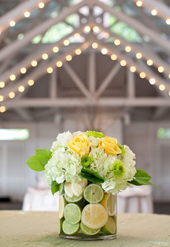 a glass vase with lime and lemon slices, red roses and white hydrangeas is great for a tropical wedding
