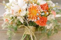 12 soft neutral bouquet with a couple of bold orange flowers wrapped with rope