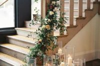 12 tree stumps with candles and a greenery and orange rose garland that interweaves the stairs